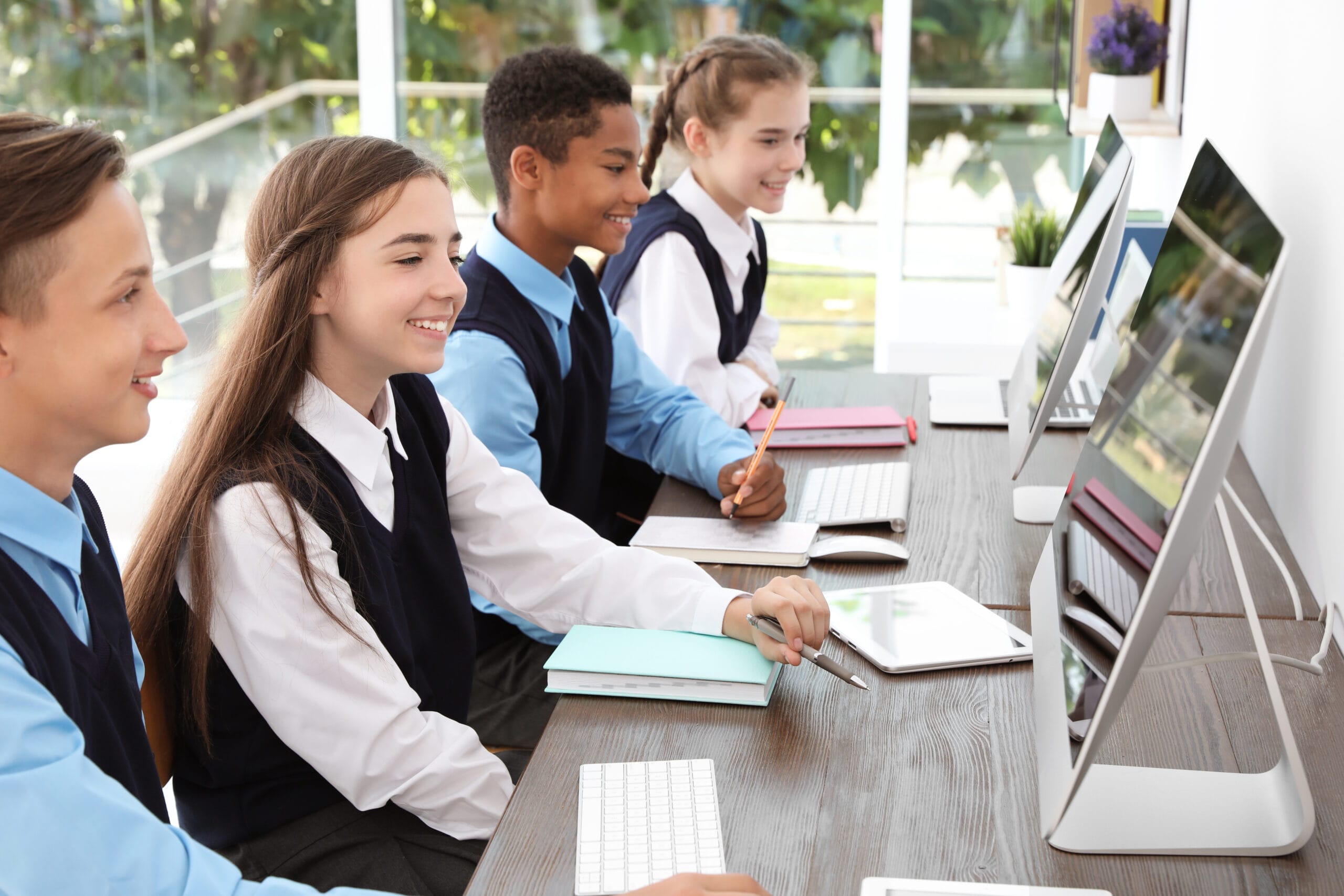 Teenage students in stylish school uniform at desks with compute